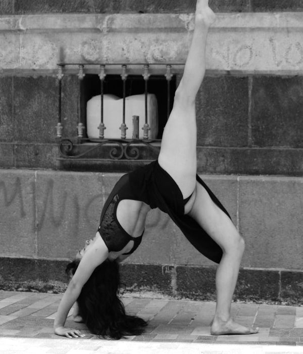 A woman performing a graceful yoga stretch outdoors.